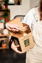 Charger l&#39;image dans la galerie, Person holding a kraft box containing reusable sugarcane knives, showcasing eco-friendly product made in France.