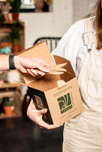 Person holding a kraft box containing reusable sugarcane knives, showcasing eco-friendly product made in France.