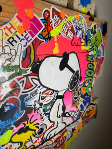 Oeuvre Pop Art de Snoopy entourée de stickers colorés, ajoutant une touche ludique à la décoration.