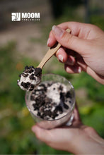 Cargar imagen en el visor de la galería, Petite cuillère biosourcée de 11 cm en main, dégustant un dessert fleuri de crèmes et biscuits.